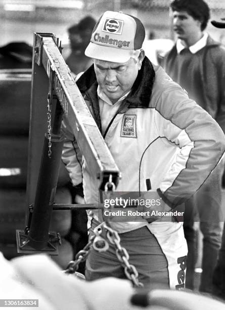 Racecar owner and legendary former driver Junior Johnson works on a racecar engine in the speedway garage prior to the start of the 1983 Daytona 500...