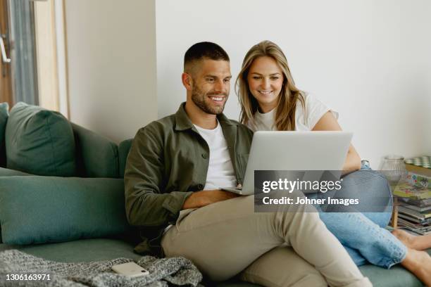 couple using laptop on sofa - ungt par bildbanksfoton och bilder