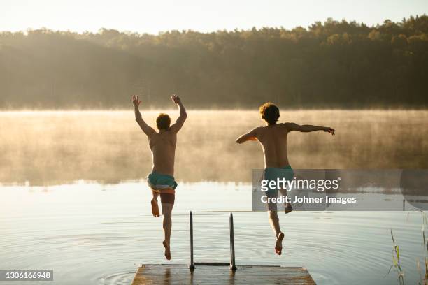 men jumping into lake - gothenburg stock-fotos und bilder