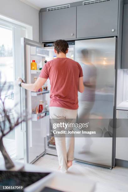 man standing in front of open fridge - open fridge ストックフォトと画像