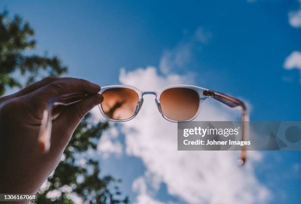 hand holding sunglasses against sky - holding sunglasses stock pictures, royalty-free photos & images