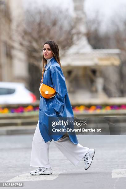 Alexandra Pereira wears a white turtleneck pullover / sweater from Zara, a blue long trench coat from Stand Studio, white flare denim jeans from...