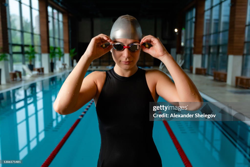 Retrato del nadador adulto caucásico en la piscina. Atleta profesional con gafas de natación está entrenando en el agua