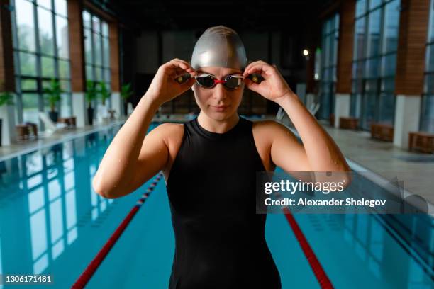 portrait of caucasian adult swimmer in the swimming pool. professional athlete with swimming goggles is training in the water - swimmer athlete stock pictures, royalty-free photos & images