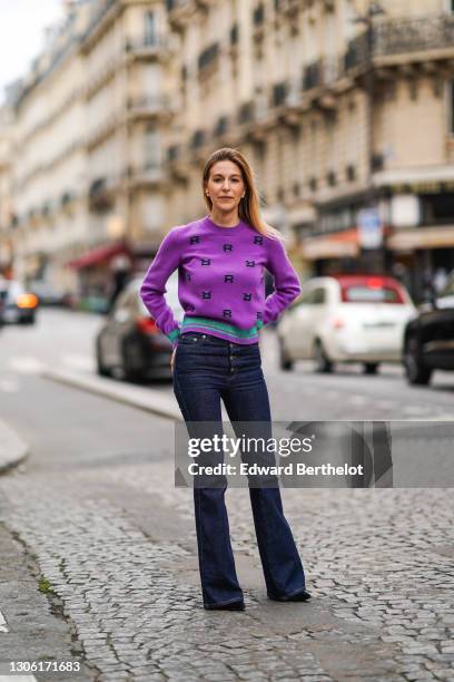 Ines Chicheportiche wears a purple wool pullover with printed letters "R" and green stripes from Sonia Rykiel, navy blue flared jeans from Sonia...