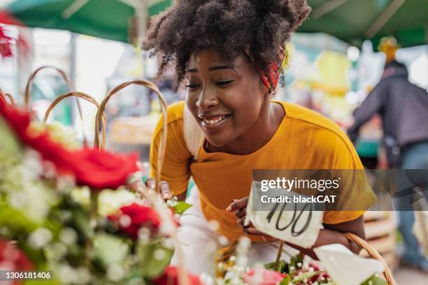joven africana comprando flores en el mercado - mercado de flores fotografías e imágenes de stock