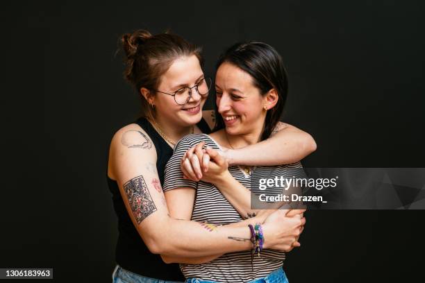 lesbian millennial couple sharing love and kissing in studio on black background - black lesbians kiss stock pictures, royalty-free photos & images