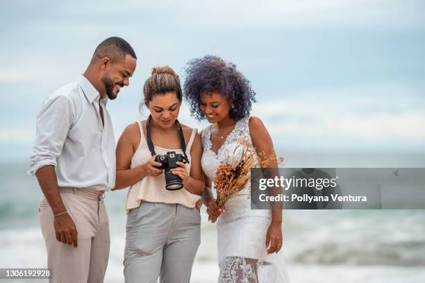 photographer shows wedding photos to the bride and groom - photographer stock pictures, royalty-free photos & images