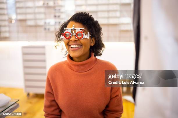 smiling woman wearing trial frame at optician - eye test equipment imagens e fotografias de stock