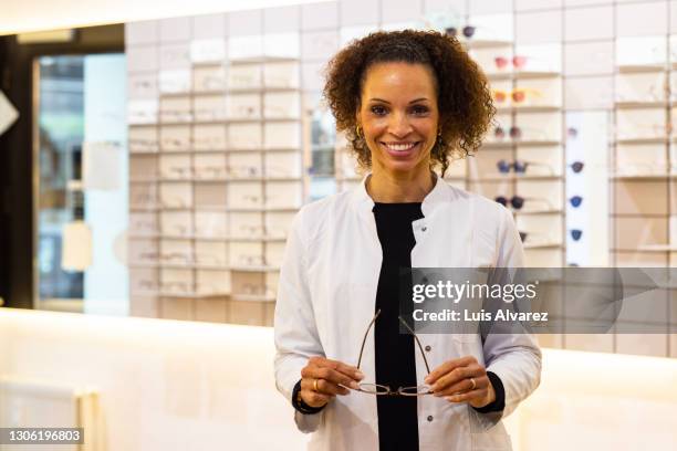 portrait of a female optometrist in optician store - optician stockfoto's en -beelden