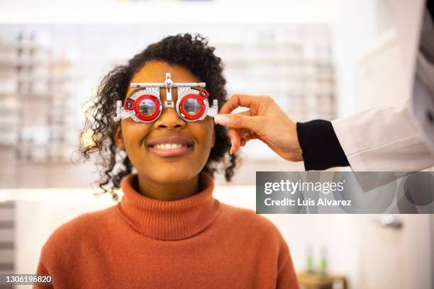 young woman having eyesight test at optical store - lente strumento ottico foto e immagini stock