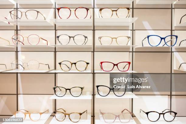 rack with different eyeglasses frames in optical store - gafas de ver fotografías e imágenes de stock