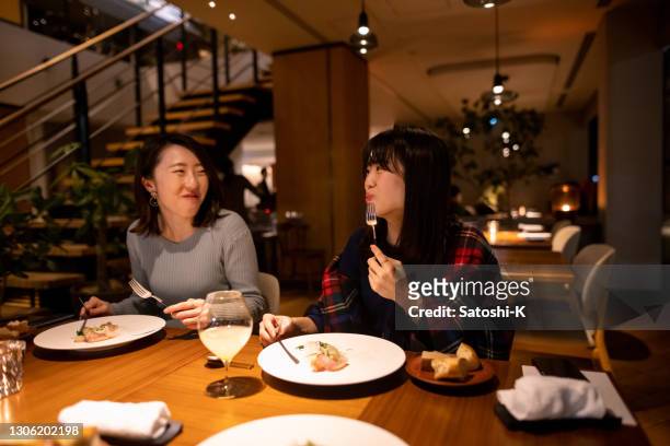 young female friends enjoying dinner in fancy restaurant - evening meal restaurant stock pictures, royalty-free photos & images