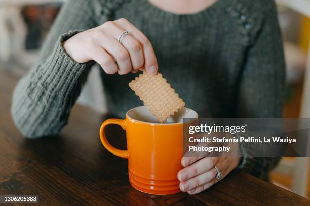 woman's hands dipping cookie in a hot drink mug - dip stock pictures, royalty-free photos & images