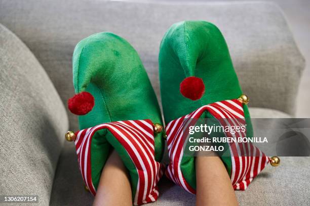 child wearing christmas elf novelty green slippers with bells on the sofa of the living room - elf feet foto e immagini stock