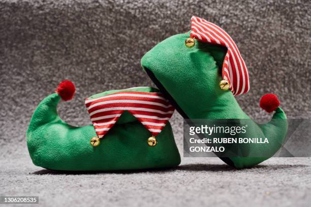 two abandoned christmas elf novelty green slippers with bells on the rug of the living room - lutin noel photos et images de collection