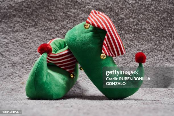 two abandoned christmas elf novelty green slippers with bells on the rug of the living room - elf feet foto e immagini stock