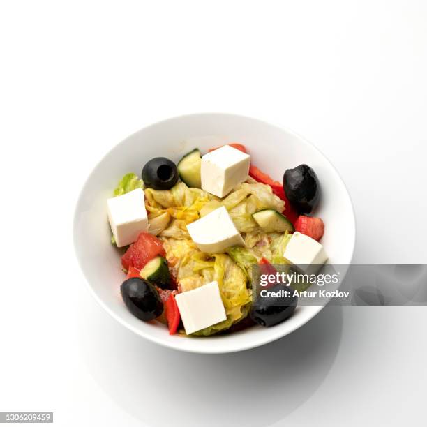 bowl of greek salad with feta cheese and olives. food plate isolated on white background. vegan or vegetarian cuisine. top view. appetizer dish from restaraunt menu. exquisite served dish - cheese top view stockfoto's en -beelden