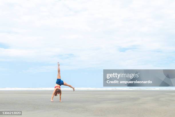 athlète féminine de gymnastique faisant le yoga d’acro et les exercices acrobatiques de gymnastique à la plage - handstand beach photos et images de collection