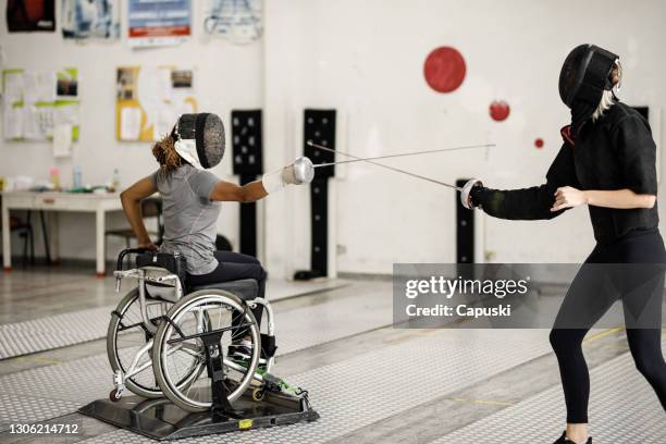 Mujer atleta de esgrima en silla de ruedas entrenando con su entrenador