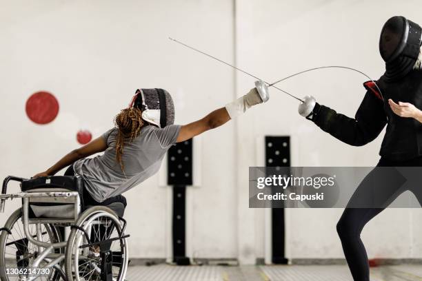 athlète d’escrimeur en fauteuil roulant féminin attaquant son entraîneur pendant l’entraînement - athlète handicapé photos et images de collection