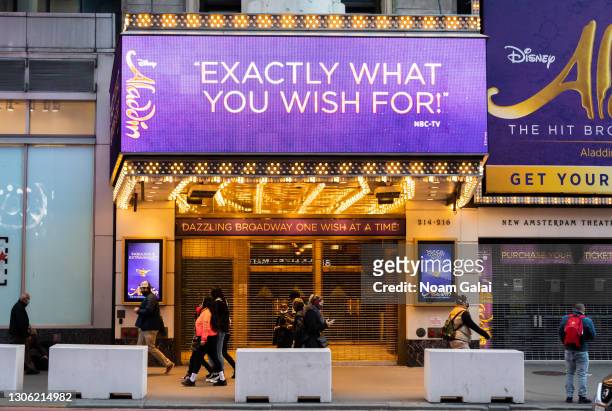 People walk by the Aladdin on Broadway at the New Amsterdam Theater in Times Square amid the coronavirus pandemic on March 09, 2021 in New York City....