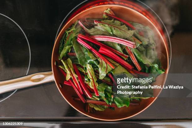 beets greens cooking in a copper pan - gaskookplaat stockfoto's en -beelden