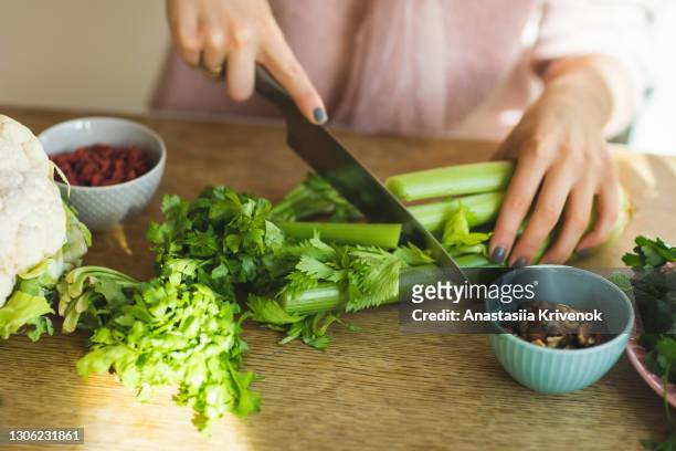 woman's hands chopping celery on kitchen counter. - bleekselderij stockfoto's en -beelden