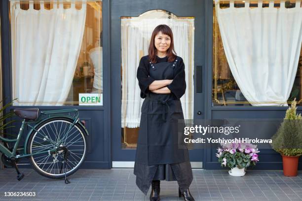 portrait of female beauty salon owner standing in front of her store - pinafore kleid stock-fotos und bilder
