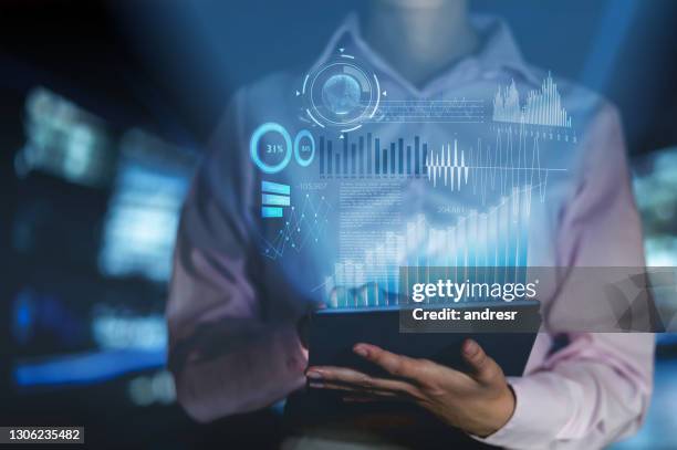 mujer analizando el desarrollo de su negocio con gráficos de hologramas en una tableta - holograma fotografías e imágenes de stock