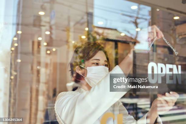 the owner who hangs an open sign on the door at an aesthetic salon. - inauguración de un nuevo negocio fotografías e imágenes de stock