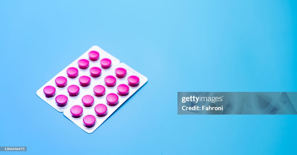 Píldoras de comprimidos rosas redondos en blíster en fondo azul con espacio para el texto. Medicina para analgésicos. Banner web de farmacia y farmacia en línea. Dolor de cabeza por migraña y pastillas para el tratamiento del dolor menstrual.