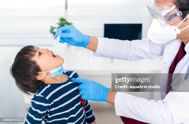 male doctor giving a child oral vaccine for prevention global pandemic - kid studio shot stock pictures, royalty-free photos & images