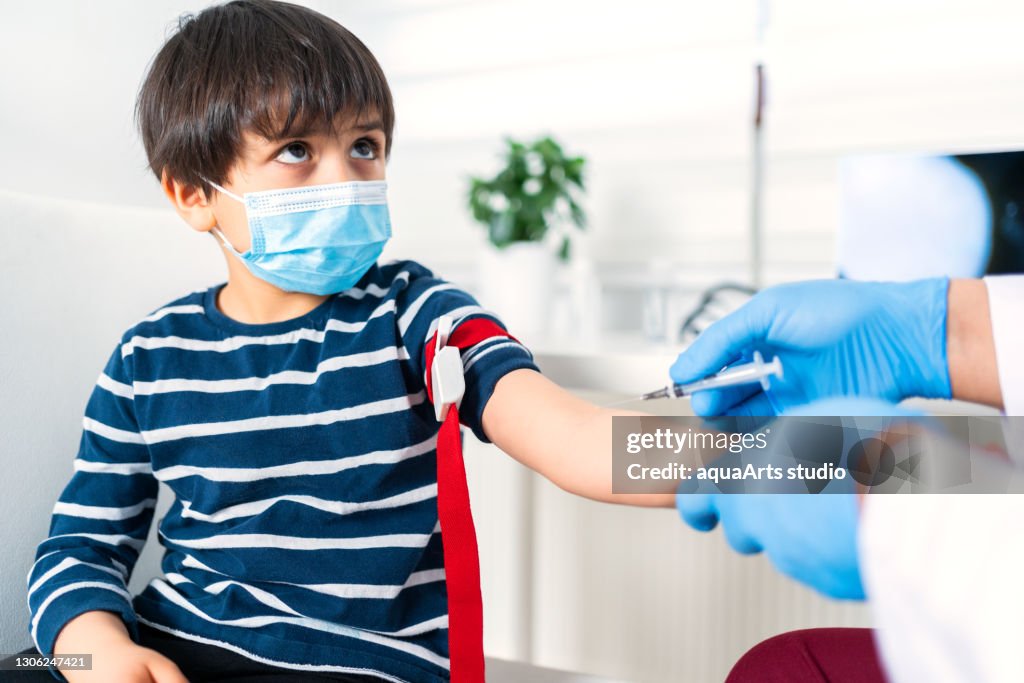 Male nurse taking blood sample of child patient ın clinic
