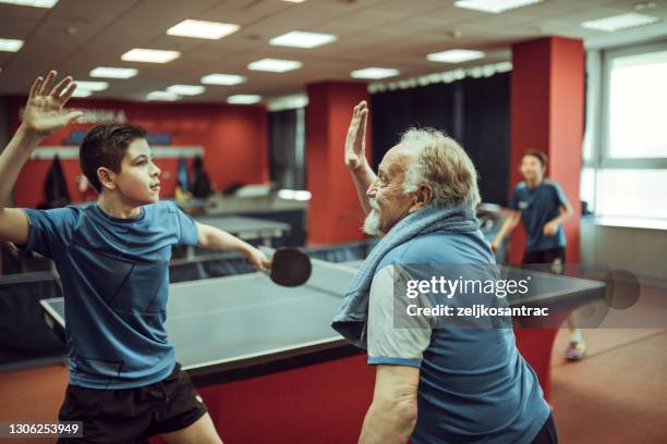nietos y abuelos juegan al tenis de mesa - ping pong fotografías e imágenes de stock