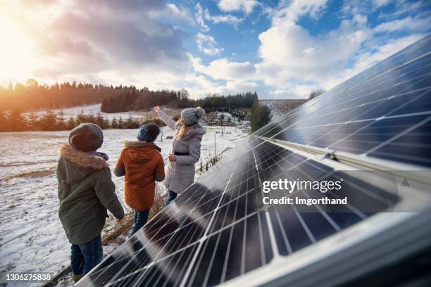 mutter erklärt den kindern an einem wintertag die technologie der sonnenkollektoren. - fuel and power generation stock-fotos und bilder