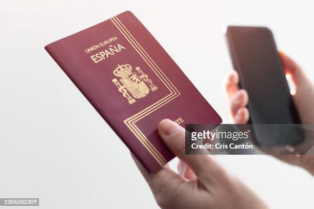 hand holding spanish passport and smartphone on white background - identity card fotografías e imágenes de stock