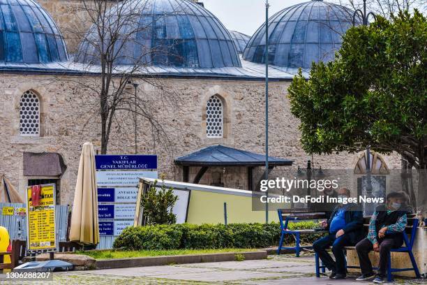 Elderly men wearing protective face masks sit on park benches on March 09, 2021 in Antalya, Turkey.