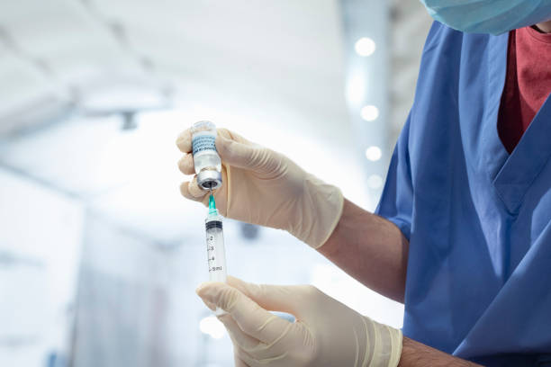 male nurse holding vial of covid-19 vaccine and syringe - covid fotografías e imágenes de stock