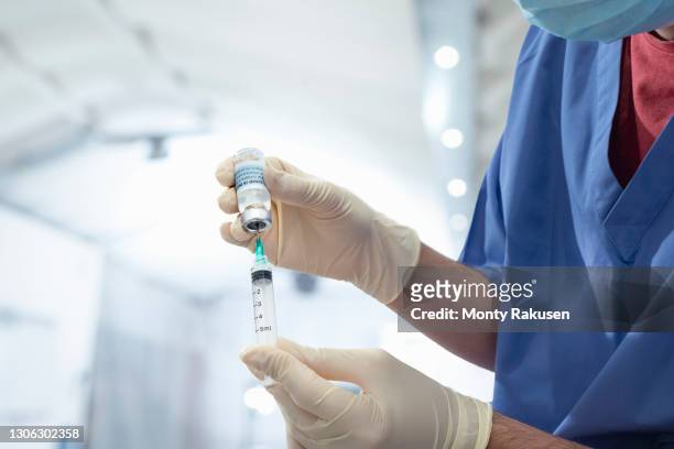 male nurse holding vial of covid-19 vaccine and syringe - young adult vaccine stock pictures, royalty-free photos & images