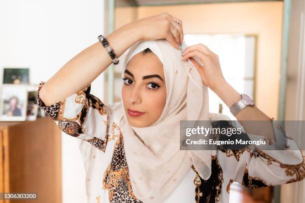 young muslim woman putting on hijab headscarf - religious veil stock pictures, royalty-free photos & images