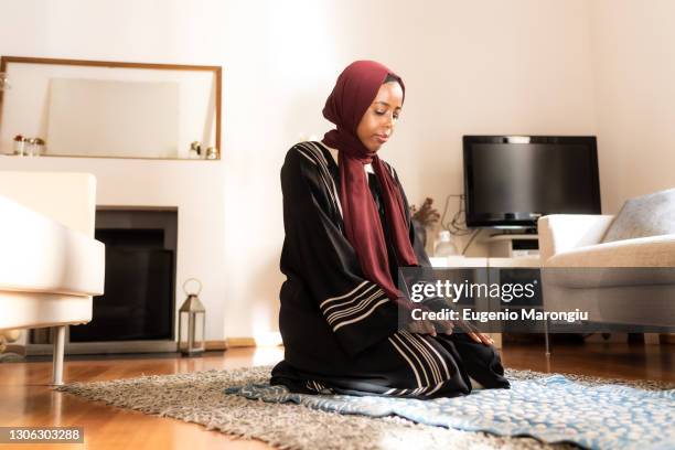 young muslim woman, kneeling during prayer - salah islamic prayer stockfoto's en -beelden