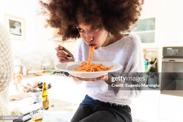 young woman eating spaghetti - spaghetti foto e immagini stock