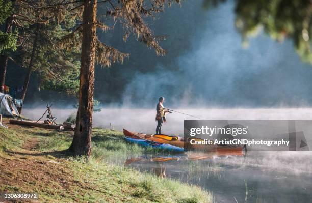 porträt einer jungen frau beim angeln beim campen neben dem schönen see. - portrait fisherman stock-fotos und bilder