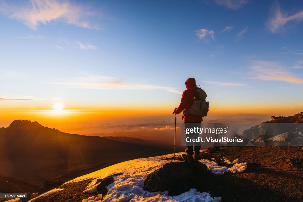 Homem caminhante realizou o sonho desfrutando do nascer do sol temor do topo da montanha Kilimanjaro