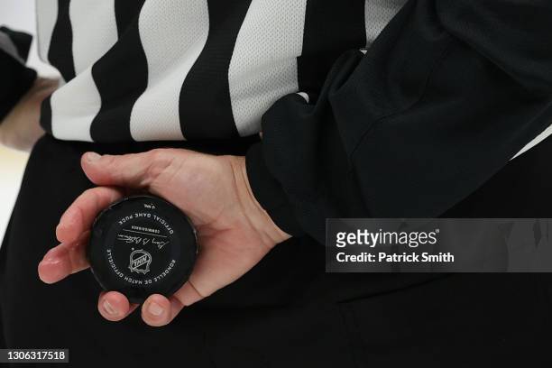 Referee holds a puck as the Washington Capitals play against the New Jersey Devils at Capital One Arena on March 9, 2021 in Washington, DC.