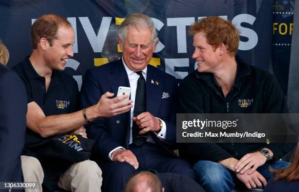 Prince William, Duke of Cambridge, Prince Charles, Prince of Wales & Prince Harry look at an Apple iPhone as they watch the athletics during the...