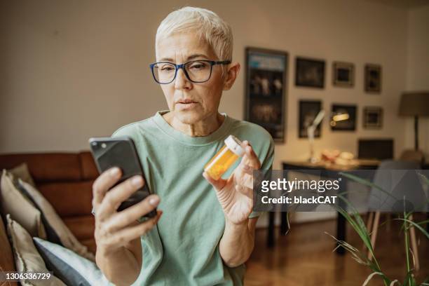 concerned senior woman searches for information about the medicine online - medicine bottle stock pictures, royalty-free photos & images