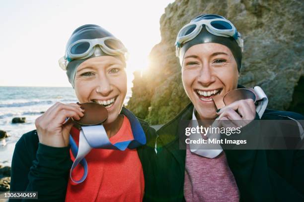 two sisters, triathletes in training in swimwear, swimhats and goggles wearing their large medals, winners. - american influence awards fotografías e imágenes de stock