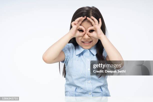 portrait of indian cute child girl sitting isolated over white background:- stock photo - ok hand sign stock pictures, royalty-free photos & images